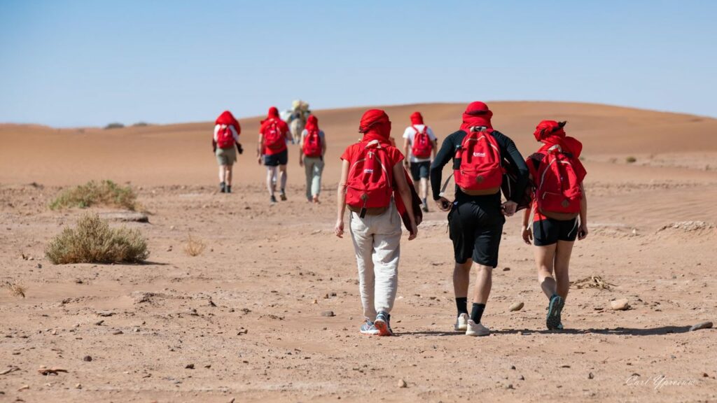 Group of participants walking through the Sahara dunes during the SDAM Évasion desert retreat